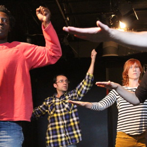 Ensemble movement exercise, 4 performers arms stretched to sides or hands raised, together with director Andrea Donaldson.